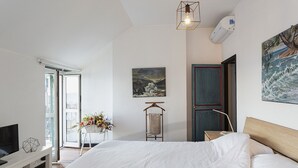 Une chambre à coucher avec un lit, une télévision, un tableau et une fenêtre.