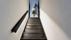 Un escalier avec une rampe métallique menant à une porte dotée d’une fenêtre.