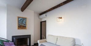 Un salon avec un canapé, une cheminée et un tableau accroché au mur.