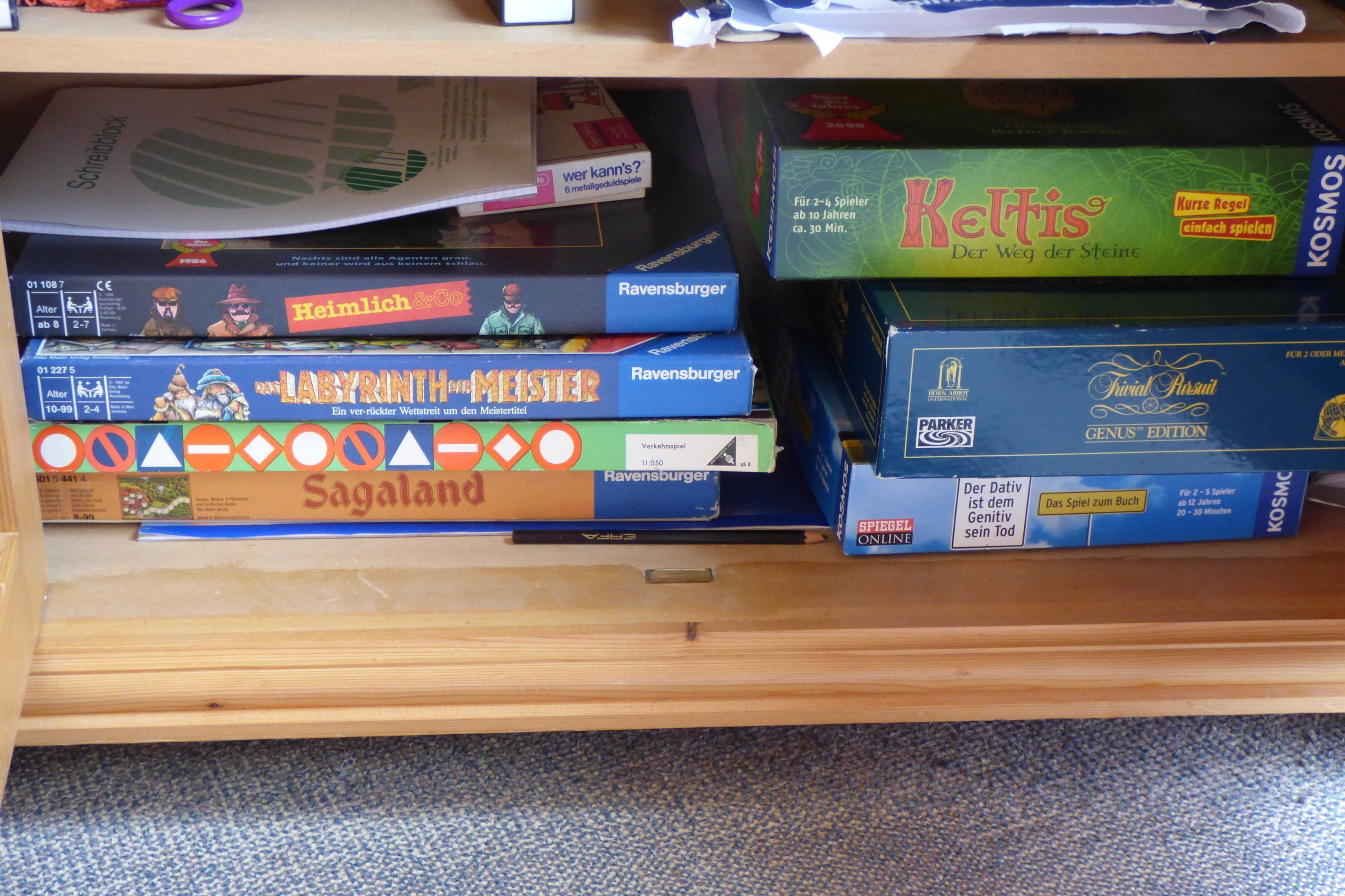 A shelf with various board games, including 'Heimlich & Co.', 'Ravensburger', and 'Keltis'.