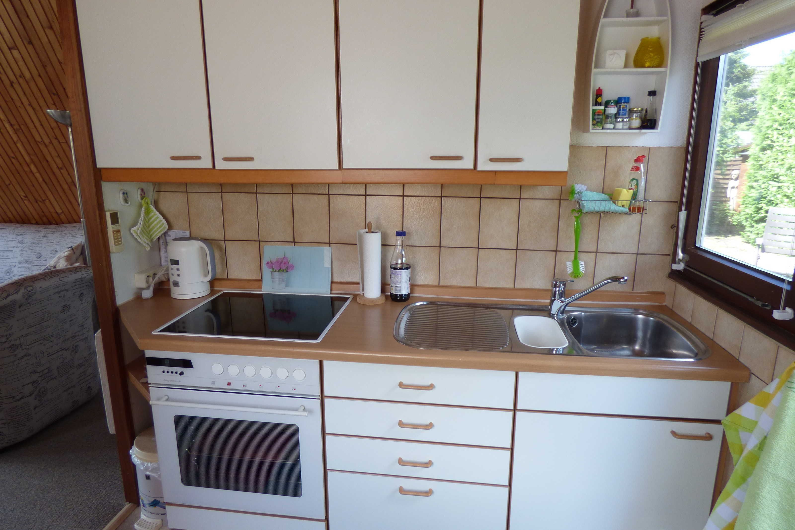 Une cuisine de taille réduite, équipée d’une cuisinière, d’un four, de deux éviers et d’une petite fenêtre.