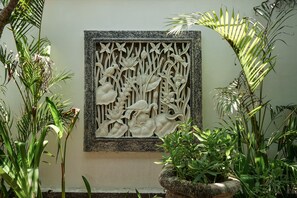 A decorative panel with floral and bird motifs, surrounded by lush greenery.