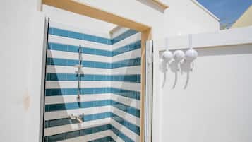 Eine Dusche mit blauen und weißen Fliesen, einem Holzrahmen und einer weißen Wand mit drei runden Leuchten.