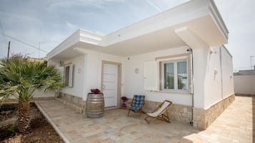 Una casa moderna con un patio, una palma, una botte e una sedia.