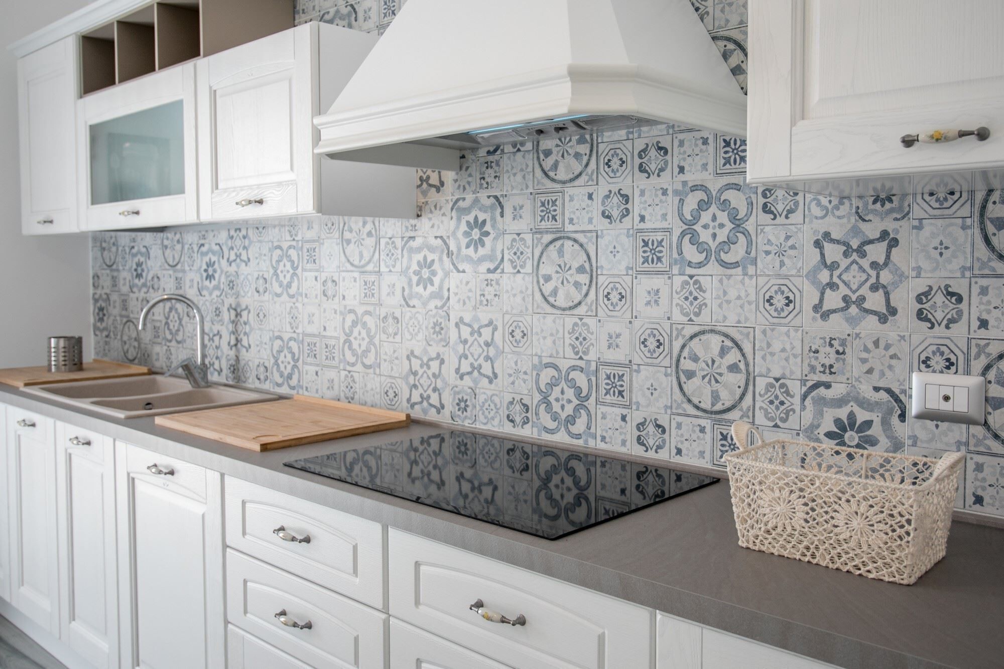Una cucina con mobili bianchi, un piano di lavoro in legno e uno schienale piastrellato con piastrelle blu e bianche.