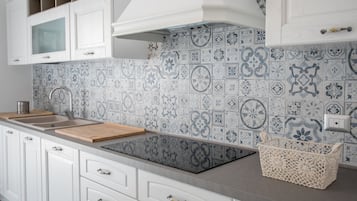 Una cucina con mobili bianchi, un piano di lavoro in legno e uno schienale piastrellato con piastrelle blu e bianche.