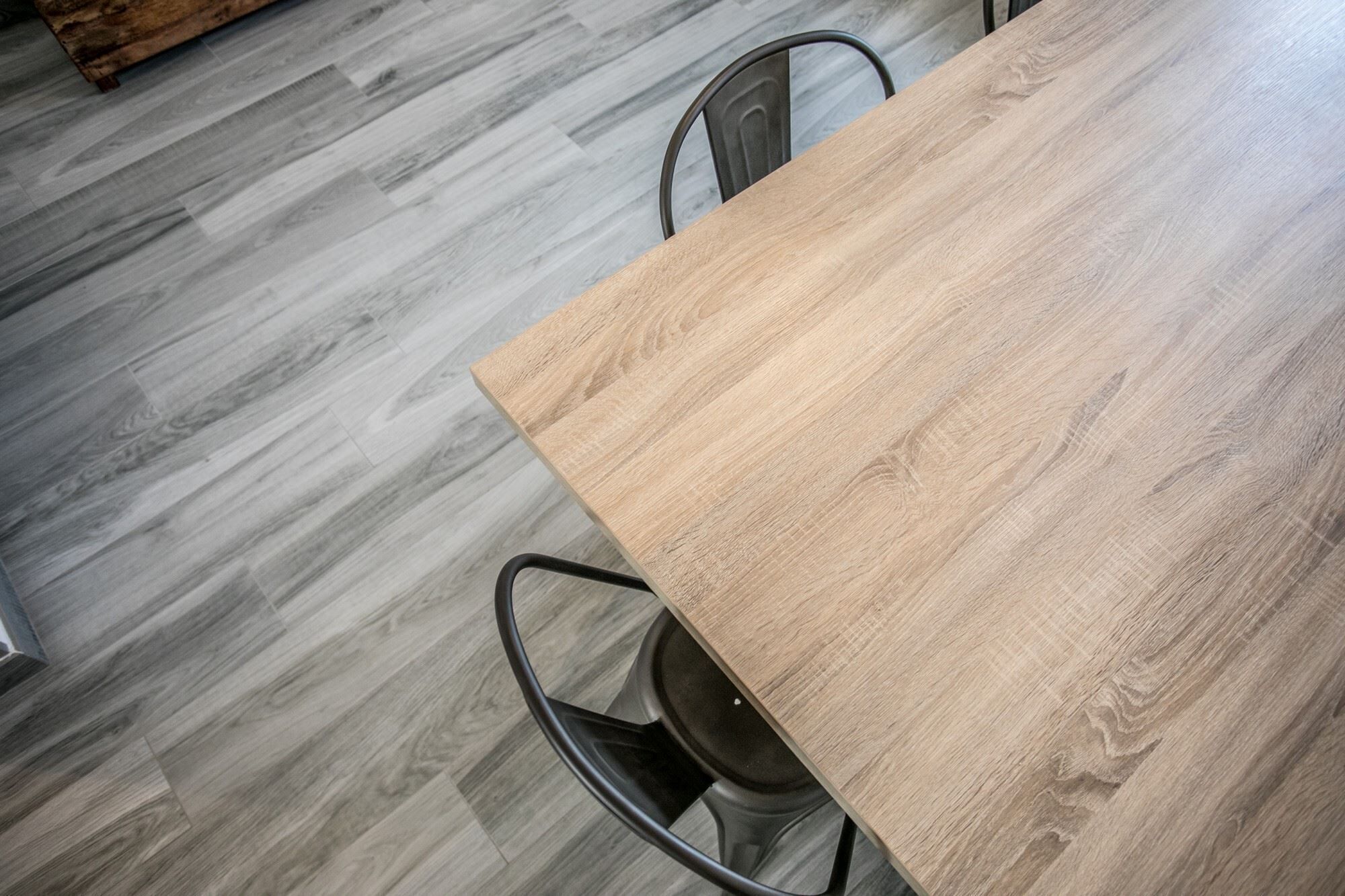 Un tavolo in legno con sedie in metallo in una stanza con pavimento in legno grigio.