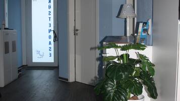 A hallway with a potted plant, a lamp, and a glass jar on a small table.