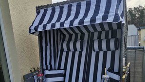 A black and white striped outdoor seating area with a small table and a drink container. - * Coastal Oasis - Wilke GM 69934 - * Coastal Oasis - Wilke SNR .: 8 (Gelbensande)