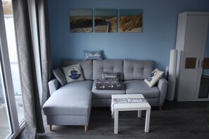 A modern living room with a grey sectional sofa, a small white table, and a white cabinet.