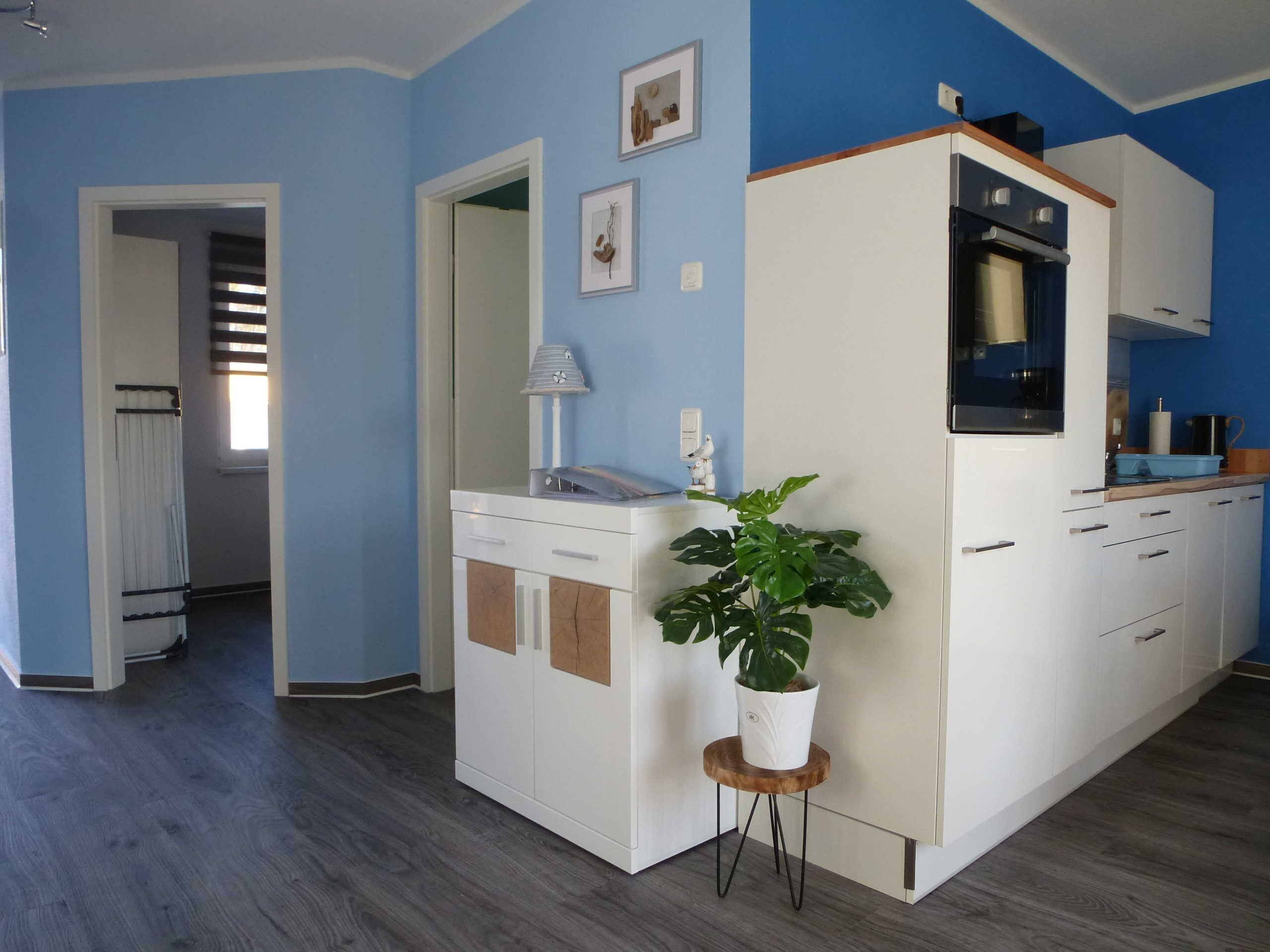 Eine moderne Küche mit weißen Schränken, einem eingebauten Backofen und einer Holz Arbeitsplatte.