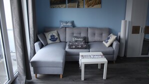A modern living room with a grey sectional sofa, a small white table, and a white cabinet. - * Coastal Oasis - Wilke GM 69934 - * Coastal Oasis - Wilke SNR .: 8 (Gelbensande)
