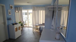 A room with a bed, a desk, a chair, a small table with a plant, and a window with curtains. - * Coastal Oasis - Wilke GM 69934 - * Coastal Oasis - Wilke SNR .: 8 (Gelbensande)