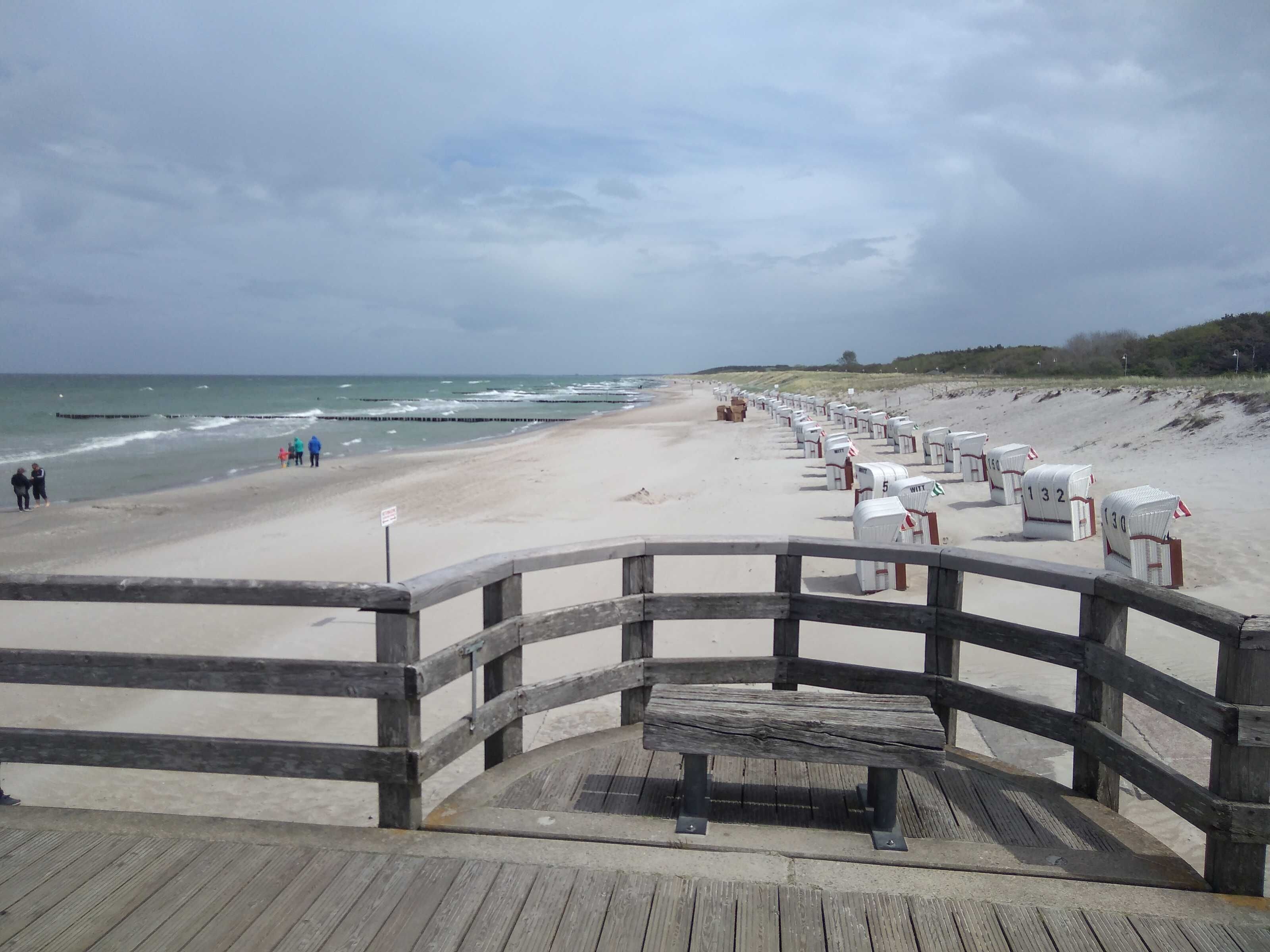 A wooden boardwalk leading to a beach with numbered beach huts.
