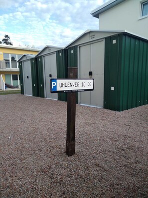 Placa de estacionamento para Uhlenweg 10 OG, um edifício com paredes externas verdes e brancas e chão de cascalho.