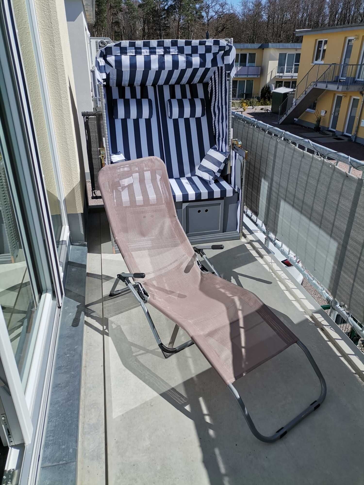 Un balcon avec un transat, un parasol à carreaux et une vue sur les immeubles voisins.