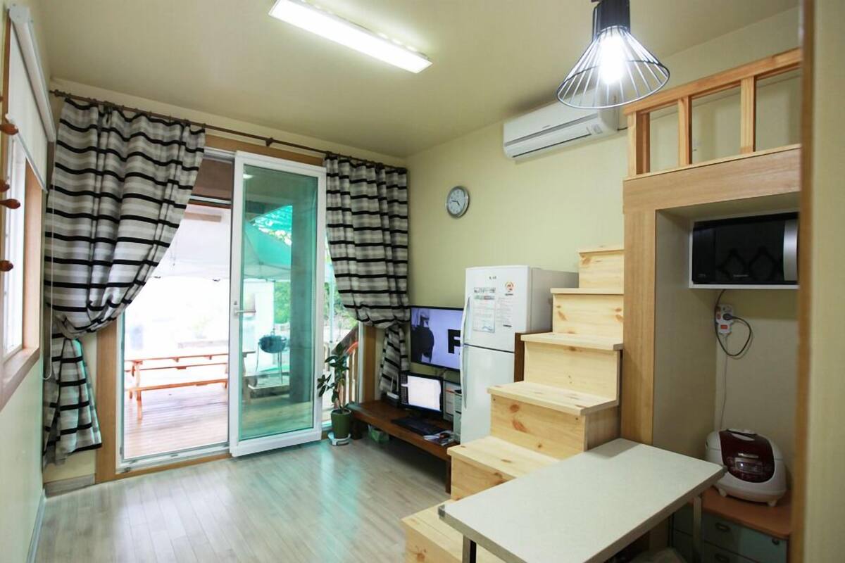 A compact room with a desk, computer, and a small staircase.