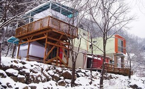 A multi-story building with a wooden balcony, surrounded by snow-covered rocks and trees.
