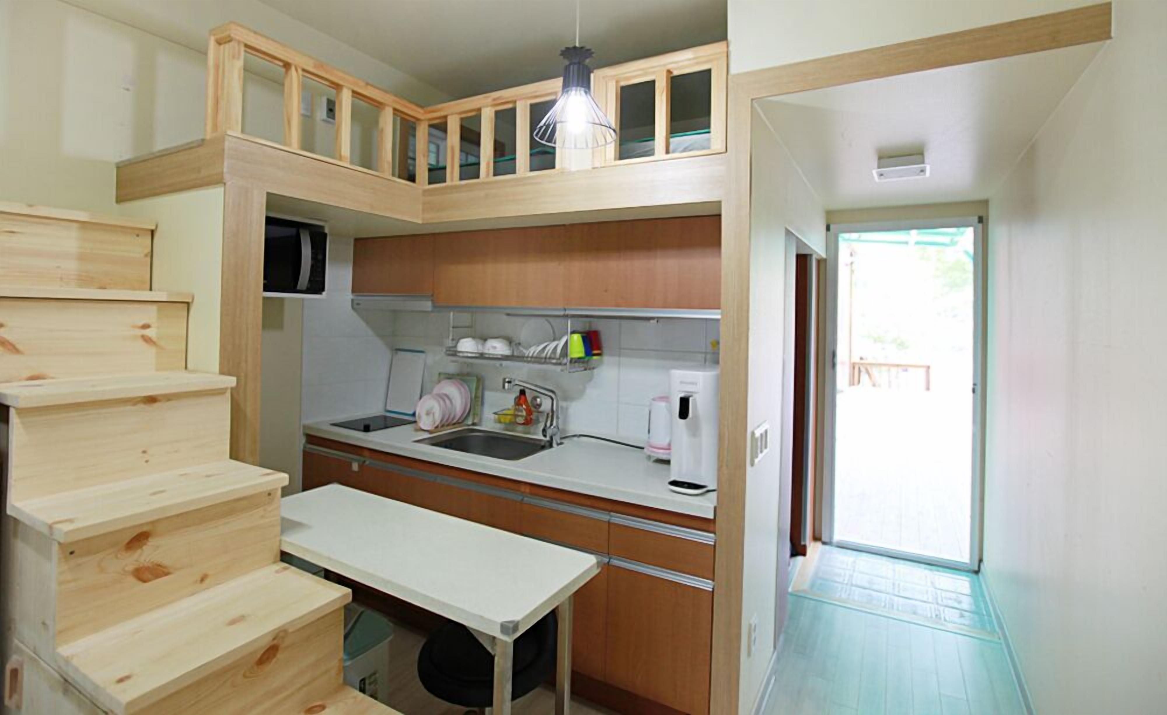 A compact kitchen with wooden cabinets, a built-in microwave, a sink, and a small dining table.