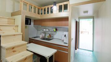 A compact kitchen with wooden cabinets, a built-in microwave, a sink, and a small dining table.