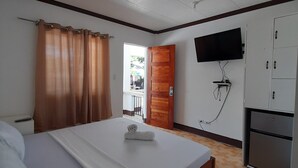 A hotel room with a bed, a television mounted on the wall, a wardrobe, and a door leading to a balcony. - Saint John Beach House (Santa Fe)