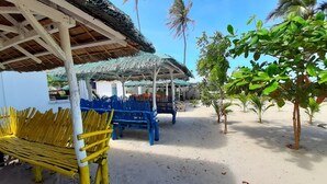 A beachside area with a thatched-roof structure, a blue bench, and a yellow bench. - Saint John Beach House (Santa Fe)