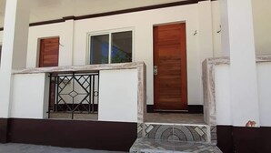 A building with a white exterior, a wooden door, a window, and a metal gate. - Saint John Beach House (Santa Fe)