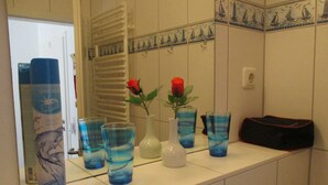 Een badkamer met een witte wasbak, een witte handdoekhouder en een spiegel met decoratieve tegels.