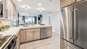 Una cocina moderna con electrodomésticos de acero inoxidable, armarios de madera y una isla grande con lavavajillas.