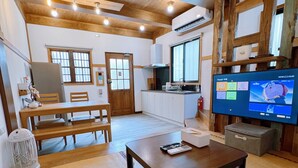 A cozy living room with a wooden ceiling, a dining area with a table and chairs, and a television displaying a cartoon. - Suehirodori Japanese Entire Home No2 (Tainan)