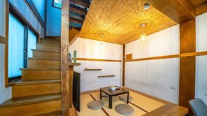 A traditional Japanese-style room with tatami flooring, a low table with cushions, and a wooden staircase. - Suehirodori Japanese Entire Home No2 (Tainan)