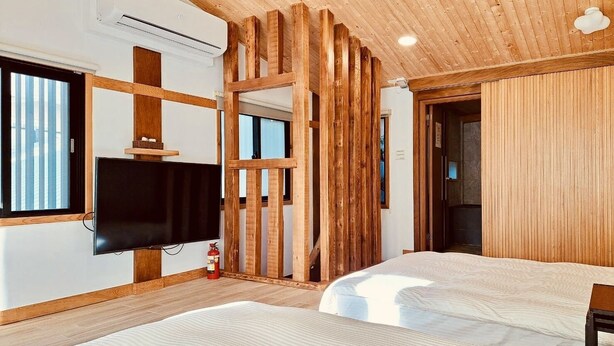 A modern room with wooden beams, a flat-screen TV, two beds, and a window. - Suehirodori Japanese Entire Home No2 (Tainan)