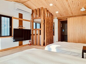 A modern room with wooden beams, a flat-screen TV, two beds, and a window.