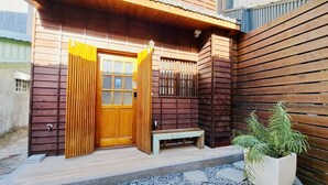 A wooden house with a wooden door and window, a small bench, and a potted plant. - Suehirodori Japanese Entire Home No2 (Tainan)