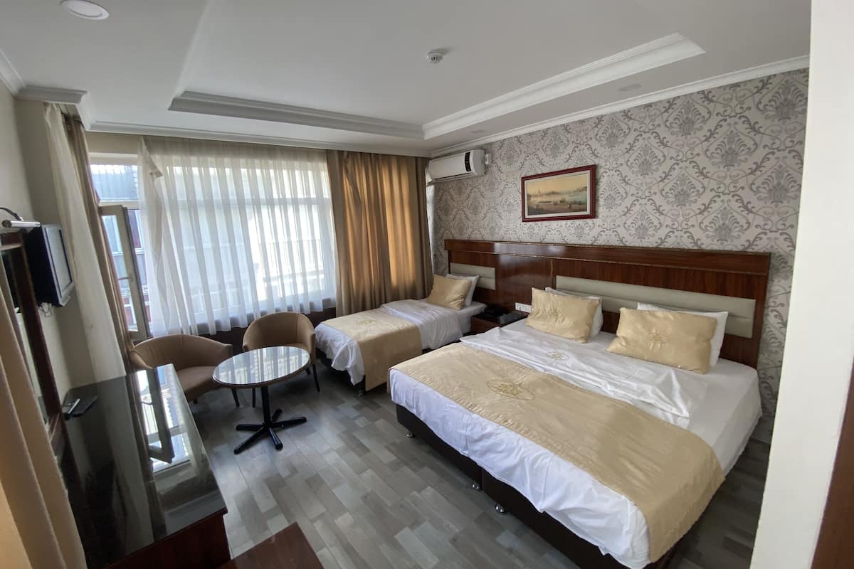 Ein Hotelzimmer mit zwei Betten, einem kleinen Tisch, einem Stuhl und einem Fernseher.