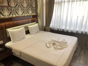 A neatly made bed with white linens and pillows, a wooden headboard, and a patterned wallpaper. - Elit Palace Hotel (Istanbul)