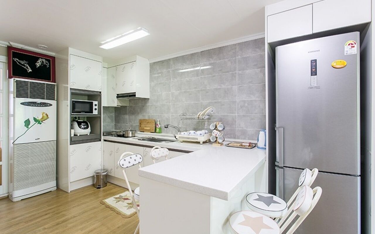 A modern kitchen with white cabinets, a stainless steel refrigerator, a microwave, and a sink.