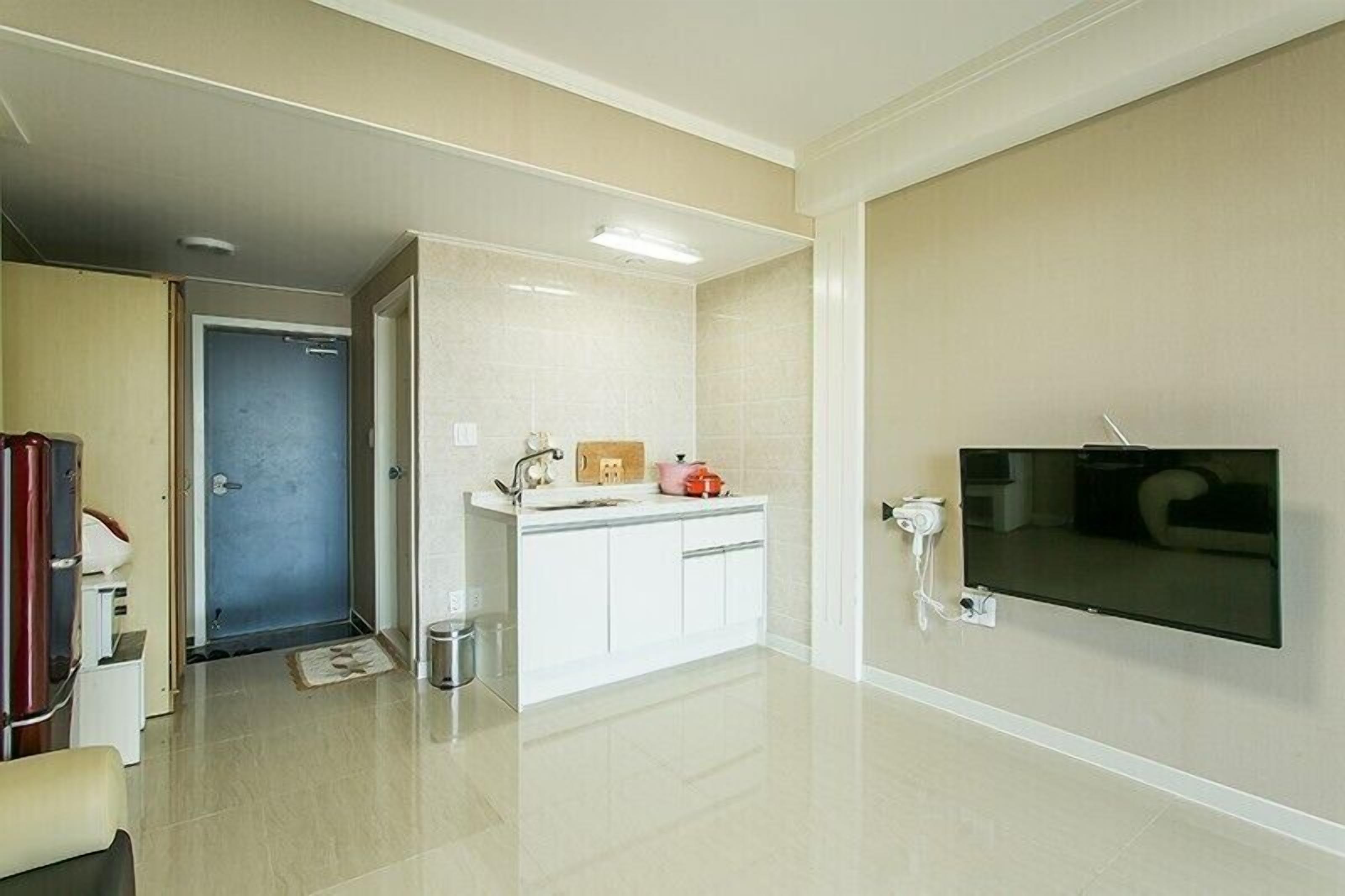 A modern bathroom with a white vanity, a large mirror, and a flat-screen TV mounted on the wall.