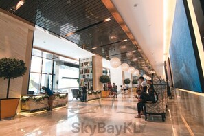 A spacious lobby with a high ceiling, large windows, and a seating area with a patterned bench.
