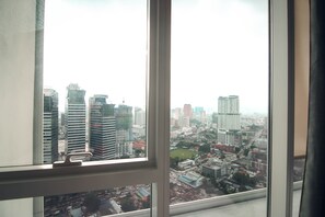 Une vue sur la ville, à travers une fenêtre, avec des gratte-ciel et un mélange de bâtiments commerciaux et résidentiels.