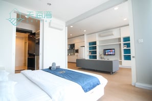 Une chambre d’hôtel moderne  équipée d’un lit, d’un bureau et d’une kitchenette.