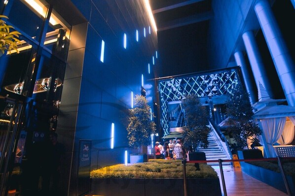 A modern building with a pool area, a staircase, and a group of people gathered near the pool.