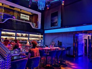 A bar area with a modern design, featuring a bar counter, seating, and a variety of bottles.