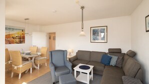 Ein modernes Wohnzimmer mit einer Couch, Sesseln, einem kleinen Tisch und einer Lampe.