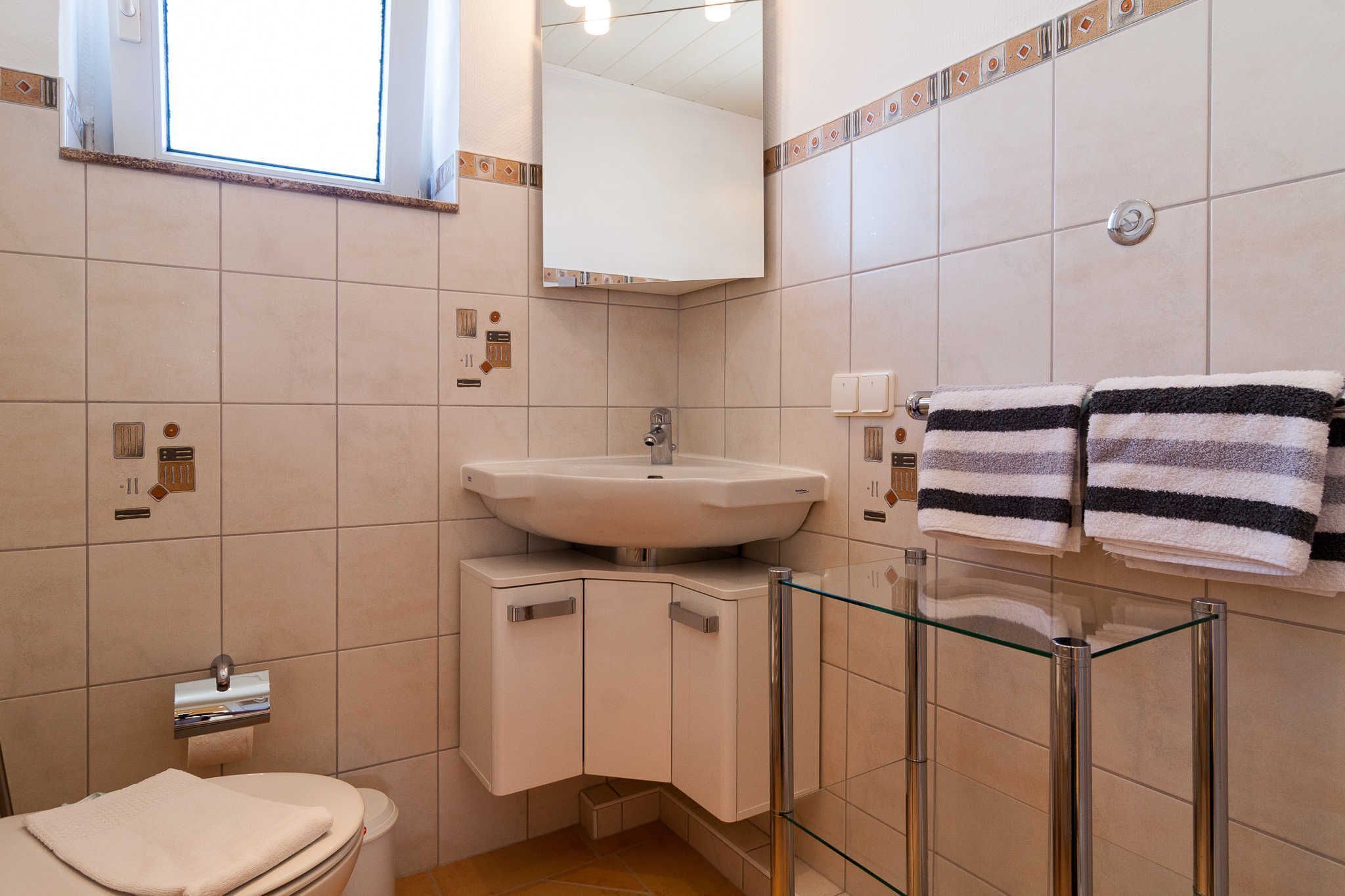 A modern bathroom with a sink, mirror, towel rack, and glass shower enclosure.