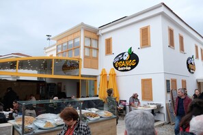Un restaurante con terraza y un edificio blanco con contraventanas de madera.