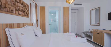 Une chambre d’hôtel avec un grand lit, une tête de lit en bois, un téléviseur fixé au mur et une armoire en bois.