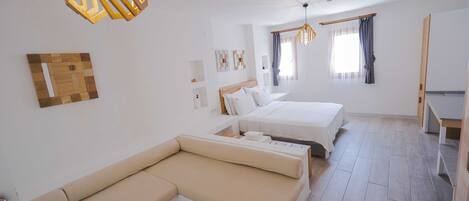 A modern hotel room with a sofa, two beds, a wooden ceiling light fixture, and a window with curtains.