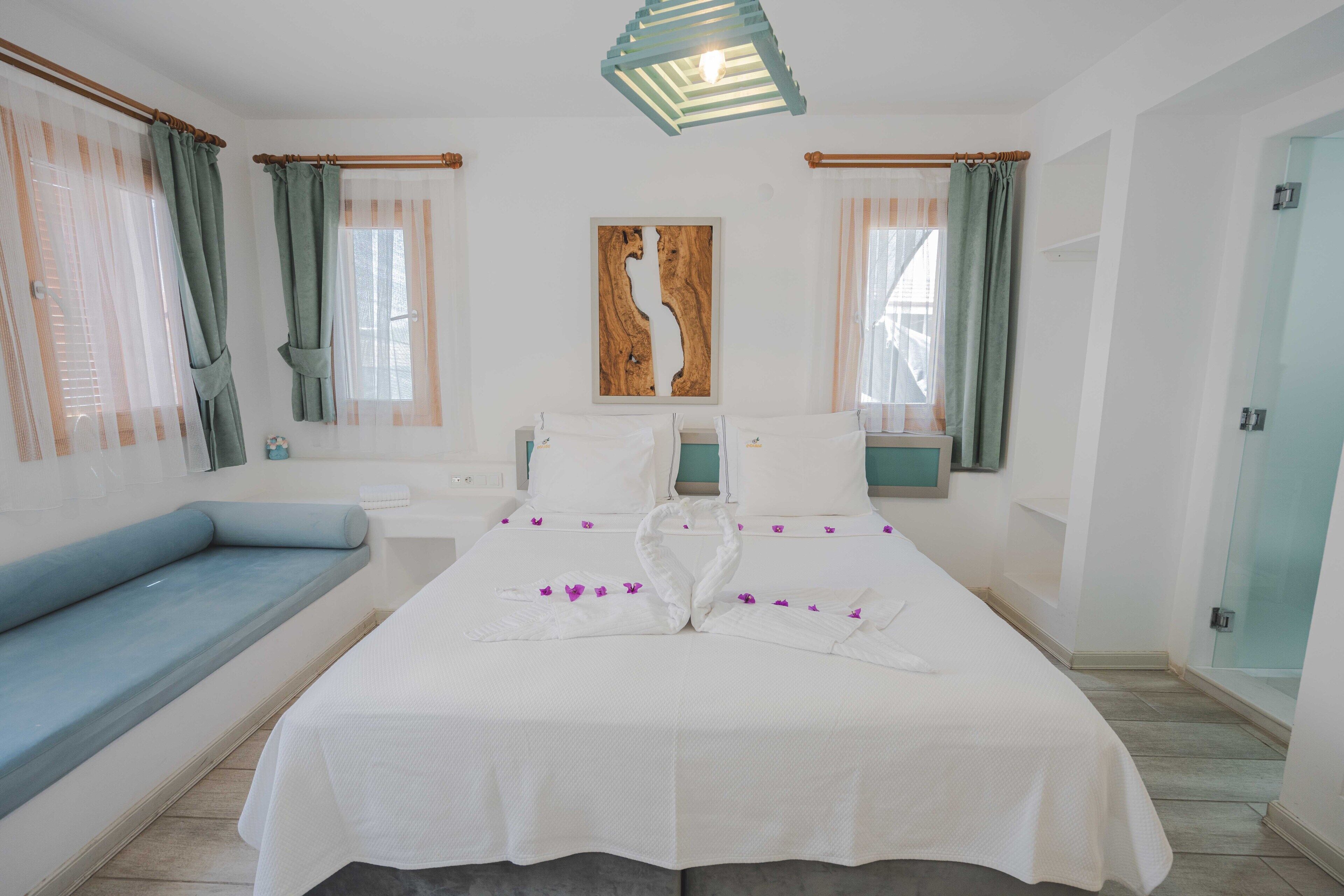 Habitación de hotel con cama, sofá azul, una obra de arte de madera en la pared y zona de ducha.