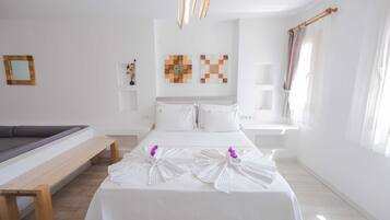 A hotel room with a bed, a bench, a wall-mounted artwork, and a window with curtains.